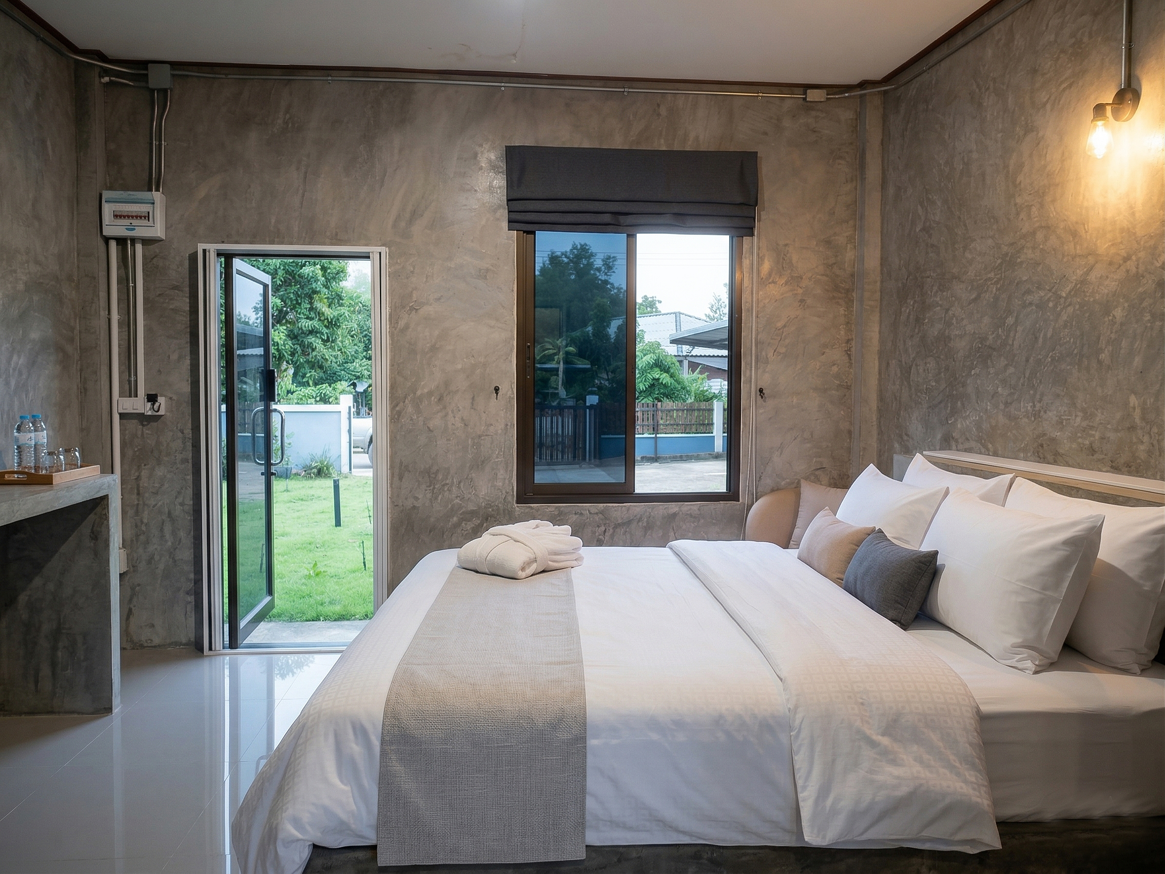 ห้องพักสไตล์ Soft Loft ของ Hana House เชียงของ ผนังปูนเปลือย ไม้ระแนง WPC แสงไฟ Warm-white